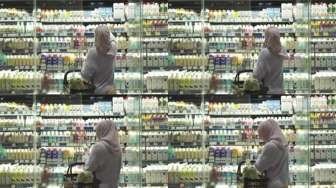 4K穆斯林妇女在超市的冷藏柜里挑选牛奶