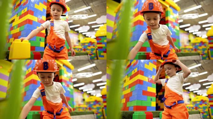 帅气的小男孩戴着建筑头盔玩着大的彩色积木。孩子在操场上玩建筑游戏。儿童教育游戏。