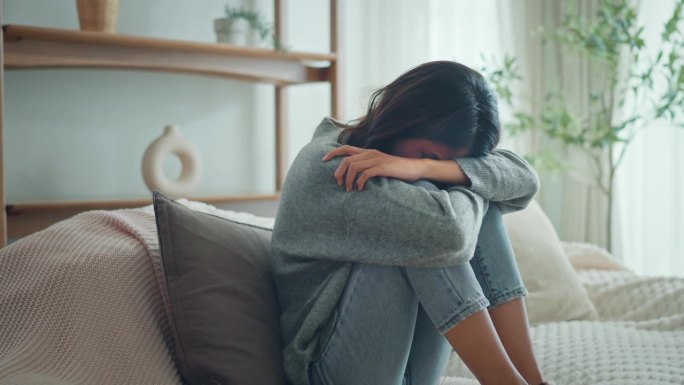 沮丧的年轻女子坐在家里客厅的沙发上，沮丧迷茫的女性在个人生活中感到不快乐的问题争吵和男友分手。