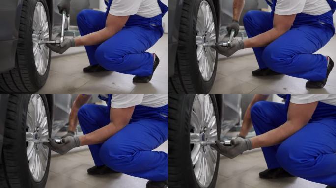 在现代汽车修理厂，穿蓝色制服的汽车技工用扭矩扳手拧紧汽车的合金车轮。熟练的技师确保豪华车的安全、精密