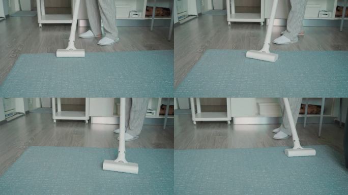 家庭主妇在客厅用吸尘器吸地毯