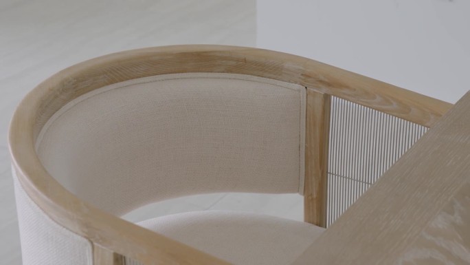 Сlose现代椅子的上视图，靠近桌子的木框，浅色布料的内部坐垫和圆形靠背
