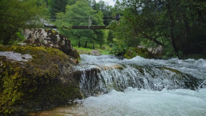 SLO莫多利拍摄田园诗般的溪流流过苔藓岩石与桥的背景在森林白天