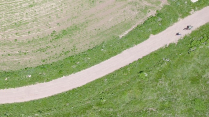 徒步旅行者和驴在走土路-自上而下的空中无人机拍摄