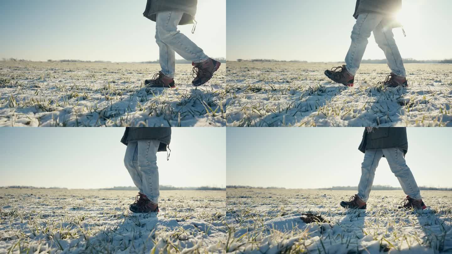 阳光明媚的蓝天下，穿着靴子的年轻女农民在白雪皑皑的农田上行走的低剖面侧视图