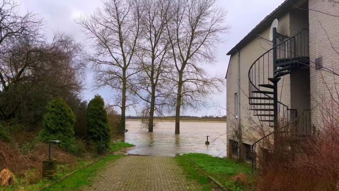 河水涌向岸边的房屋，有可能淹没建筑物