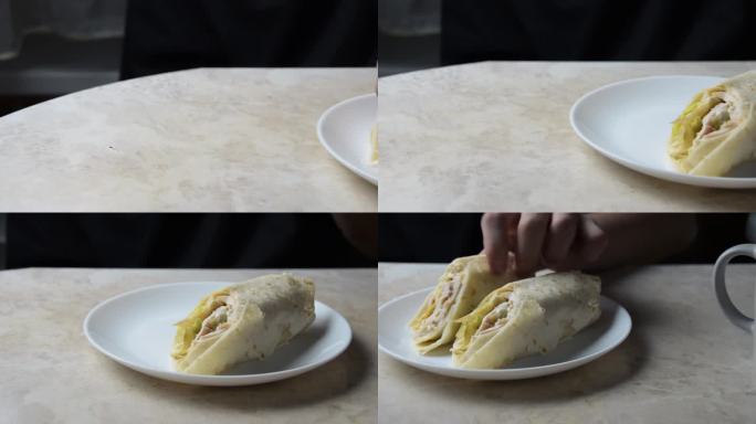 一个年轻人从盘子里拿出一块沙瓦玛吃了起来。电影画面。从左到右的通道。