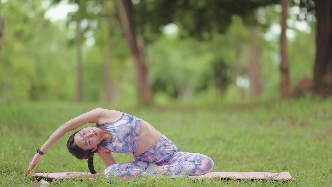 年轻女子保持健康和身材，在公园户外做瑜伽