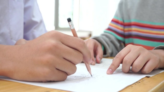 亚洲学生在课堂上使用橡皮擦书写学习考试。在高中的教育。学校学生的阅读笔记，评估在同学入学答卷上的写作