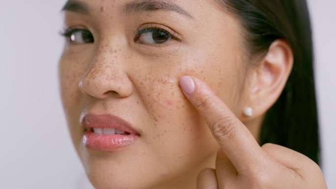 女人，用洗面奶或化妆品接触脸部和皮肤，在工作室里美容。手指，亚洲女性和胶原蛋白治疗自然焕发，护肤和健