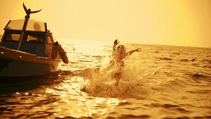 一对无忧无虑的夫妇在日落时分从船上跳入海水