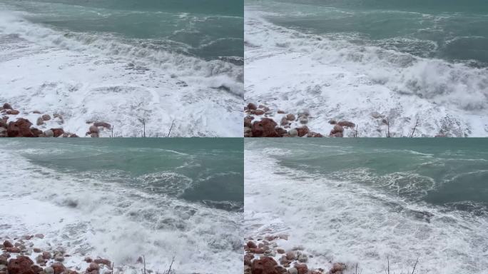 蓝色的泡沫海浪覆盖着靠近海岸的圆形石头