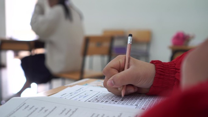 亚洲学生在课堂上使用橡皮擦书写学习考试。在高中的教育。学校学生的阅读笔记，评估在同学入学答卷上的写作