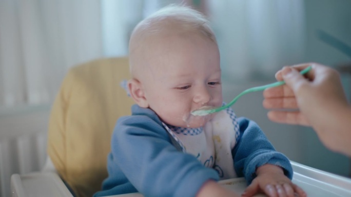 母亲给婴儿喂食的小手。固体食物。引入固体食物