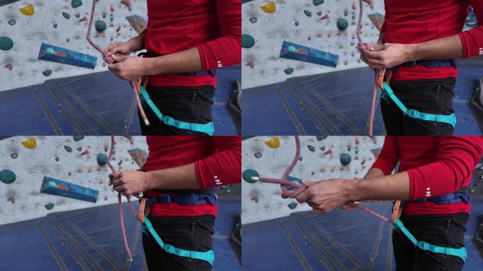 在攀岩墙的底部准备攀爬，一名攀岩者熟练地使用先进的打结技术固定攀岩绳。