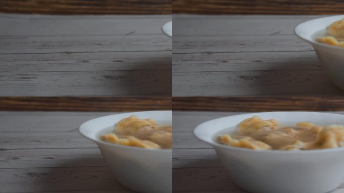 木桌上盛着汤圆的盘子。摄像机的通道是从左到右的。