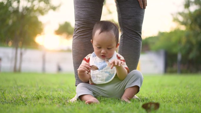 母亲带着男婴在公园户外玩耍