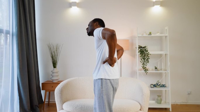 不快乐的黑人在家里忍受着背部疼痛和缰绳疼痛