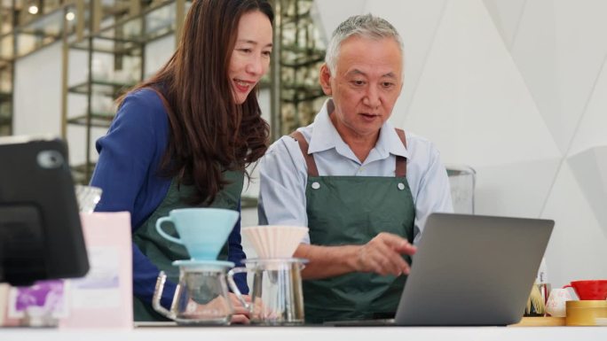 咖啡店老板兼助理，为店铺的成功分析销售情况。穿着围裙的咖啡店老板和她的助手在舒适的咖啡馆里用电脑分析