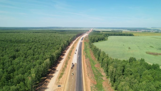 新建高速公路的鸟瞰图。为了修路而砍伐森林。这条在建的路一直延伸到远处。
