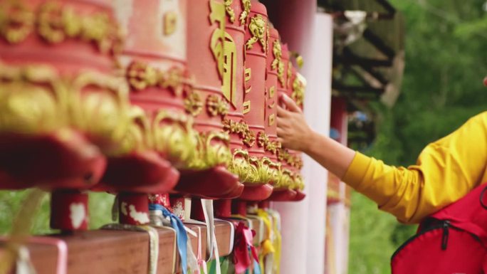 在佛教寺院，一位女朝圣者的手触摸着转动的经轮。佛塔寺庙里的经轮。佛教的宗教观念。