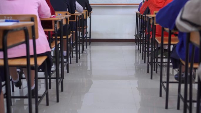 在高中与后面的女生亚洲学生组集中考试笔试，用泰国学生制服在教室认真地拿着期末考卷。教育评价回归学校