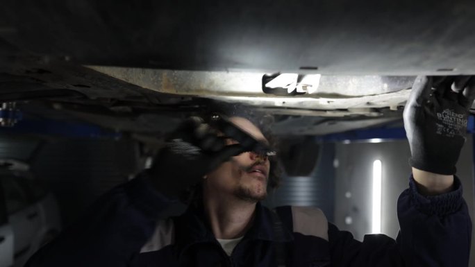 汽车修理工在汽车修理厂工作，检查车身和悬挂系统