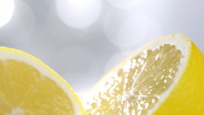 切片柠檬旋转在慢动作对模糊的白色背景，微距镜头
