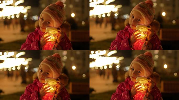 一个小女孩穿着暖和的冬衣，在寒冷的室外用手电筒照着她的脸。实现梦想的概念，追随你的欲望