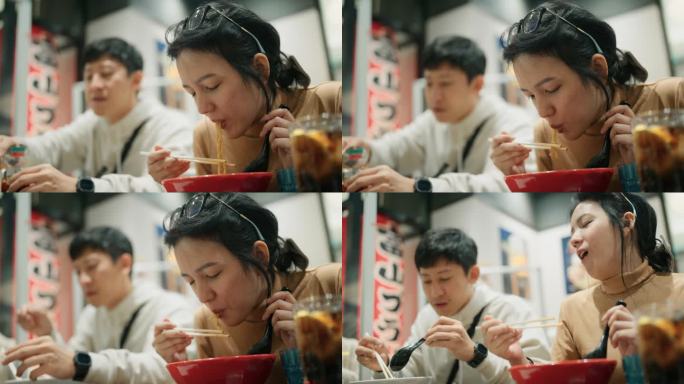 幸福的亚洲夫妇用筷子夹方便面和吃热日本拉面在日本餐馆
