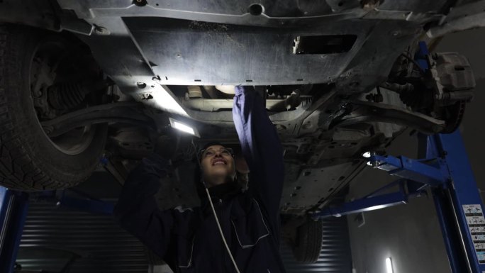女汽车修理工在汽车修理厂工作，检查汽车的车身和悬挂系统