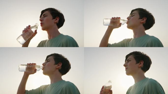 男性在炎热的时候贪婪地喝着瓶子里的水，骑自行车散步，暑假后锻炼或运动日落特写。白种人男孩在大热天喝矿