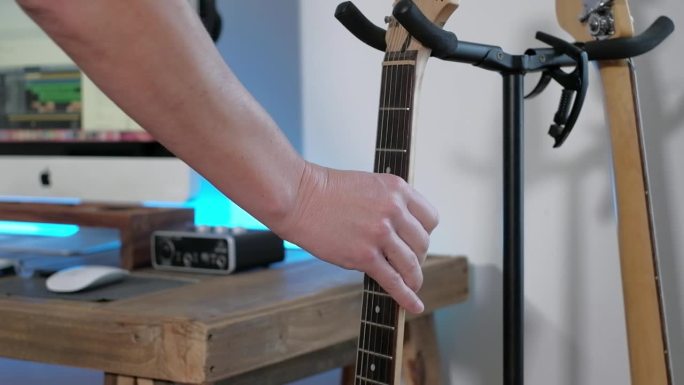 一名男子在录音室里弹奏吉他独奏、和弦和贝斯节奏的中镜头，重点放在双手上