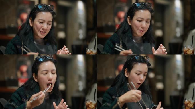 快乐的亚洲女人在一家餐厅吃着日式烧烤，和她的朋友聊天。