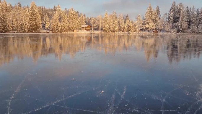 在阿尔卑斯山美丽的冰湖上滑冰，背景是木屋和白雪覆盖的树木。