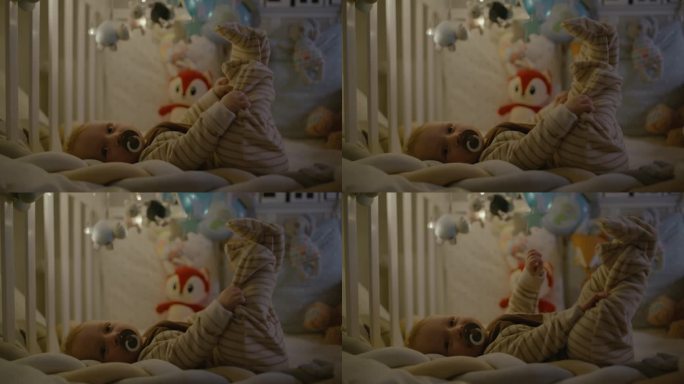 男婴躺在床上，嘴里含着奶嘴，脚举在空中