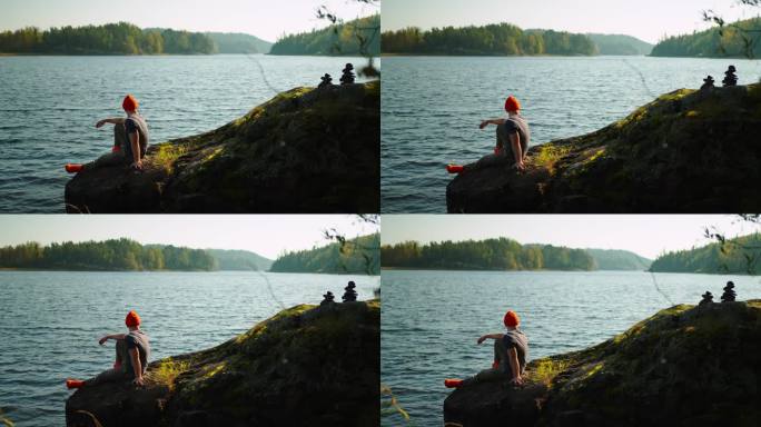 独自去大自然旅行，年轻的成年男子坐在湖边的石头上观看自然景观