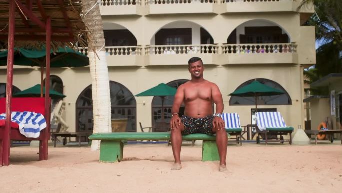 夏天，一个光膀子的男人坐在海滩度假胜地的长椅上