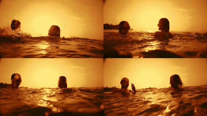夕阳下，一对无忧无虑的夫妇张开双臂在宁静的海水中游泳
