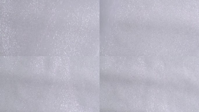 银色闪光的化妆品在白色的背景下流淌。带着微光的乳液滴在画布上倾泻而下。银光闪闪的油漆滴在白色的墙上
