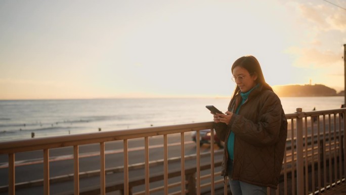 孕妇站着用智能手机拍摄美丽的日落背景