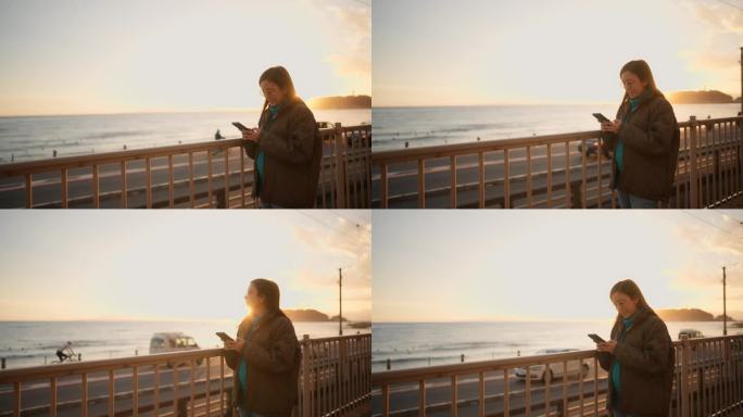 孕妇站着用智能手机拍摄美丽的日落背景