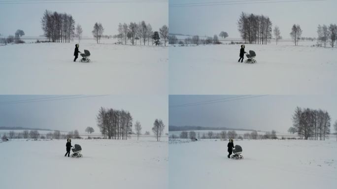 单亲妈妈推着婴儿车走在雪道上，冬天风景优美