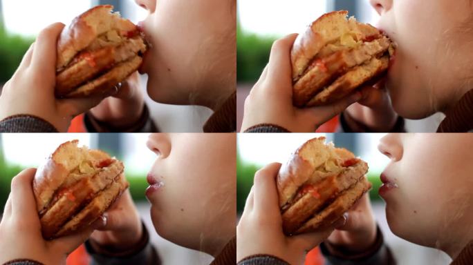 吃汉堡的女孩特写。一个孩子在吃汉堡包。快餐。汉堡在女人手里。一个饿着肚子的女人在咖啡馆吃汉堡的侧面照
