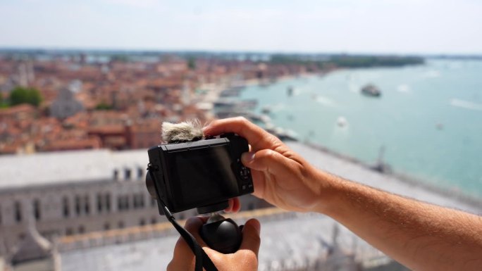 男性双手操作小型相机，从康铂酒店的角度拍摄视频