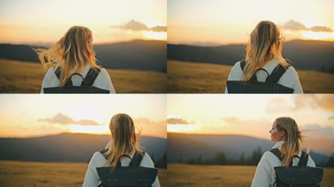 年轻的金发女郎背着双肩包在日出时欣赏山景
