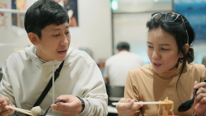 一对亚洲夫妇在旅行中休息时在日本餐厅吃茶树拉面。