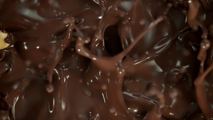 剥皮榛子落入旋转融化巧克力的超级慢动作镜头，1000 fps。