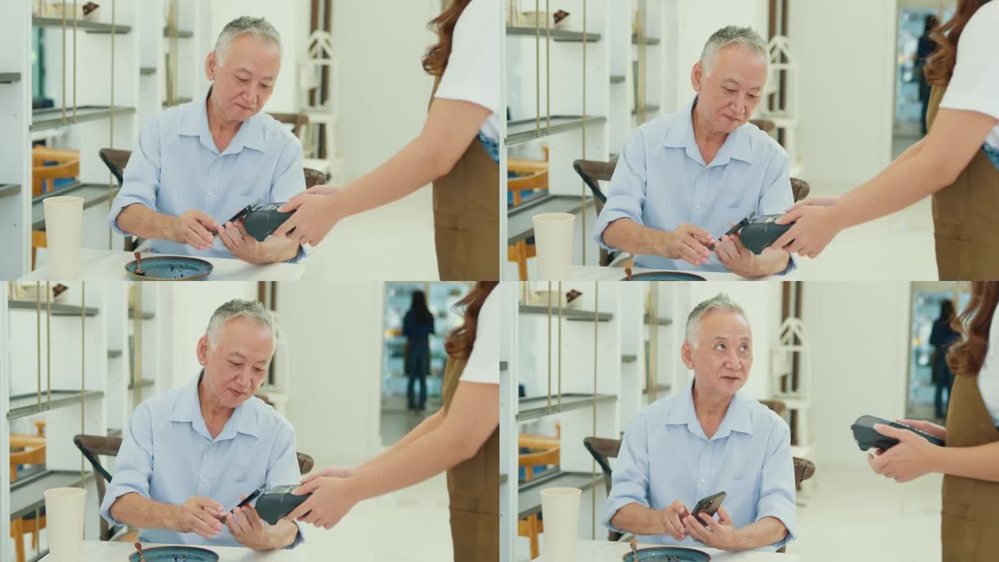 一位年长的亚洲男性顾客在现代咖啡馆用智能手机进行移动支付，展示了现代支付的便利性。小企业主。