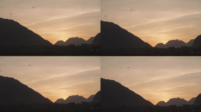 日落时分，在老挝的旺永，喀斯特山脉的背景下，一个动力降落伞